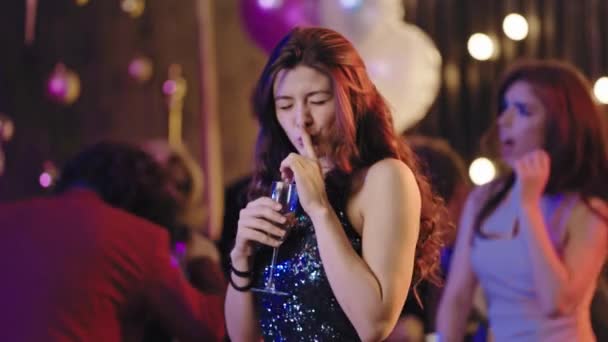 Smiling attractive young woman ina glamorous dress at big party in front of the camera enjoying the time at party drinking champagne and feeling relaxed. Shot on ARRI Cinema Camera — Wideo stockowe