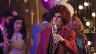 Charismatic in a casual suit guy make a funny faces in front of the camera at big glamorous party he enjoying the time drinking some champagne and dancing