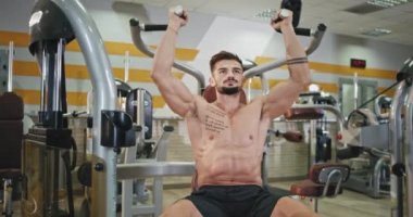 Kameranın önünde profesyonel kaslı adam, pazılarına ve pazılarına daha fazla kas yapmak için konsantre oluyor.