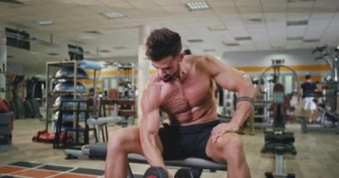 Full of muscle body good looking man exercises to get more fit and strong doing exercises for his biceps in a modern gym class