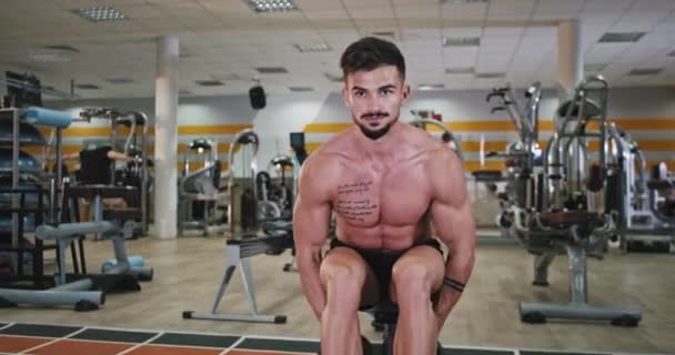 Dans un cours de gym avec grand endroit spacieux homme athlétique faisant des exercices très concentrés pour son muscle pour obtenir un corps en forme et fort. 4k — Video