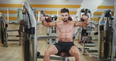 İyi görünümlü atletik mutlu ve güneşli bir spor salonunda bisepsleri ve trisepsleri üzerinde çalışıyor. Sağlıklı bir yaşam tarzı var. 4k