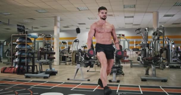 Homem atlético atraente fazendo exercícios concentrados em uma classe de fitness que ele trabalha para seu corpo para obter mais músculo e ter um corpo forte — Vídeo de Stock