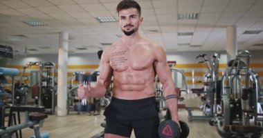 Daha fazla kas yapmak için formda vücut egzersizleri yapan karizmatik bir adamın önünde sporunu bir fitness stüdyosunda yapıyordu. 4k
