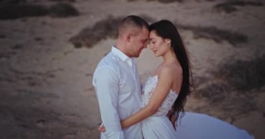 Çekici romantik çift doğanın ortasında mükemmel vakit geçiriyorlar. Kum tarlasıyla dolu. Birbirlerine sarılıyorlar.