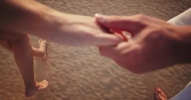 Sahilin ortasında birbirine aşık harika bir çift gün batımında el ele yürüyorlar.