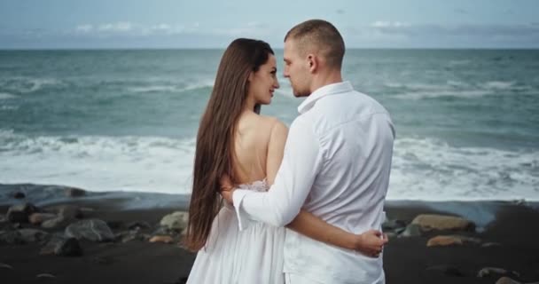 W środku niesamowitego nadmorskiego krajobrazu romantyczna młoda para świetnie się bawi, przytula się i czuje się zakochana.. — Wideo stockowe
