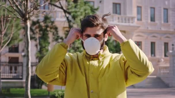 Charismatic guy outside in the middle of the street get on his face protective mask for new Covid-19 — Stock Video