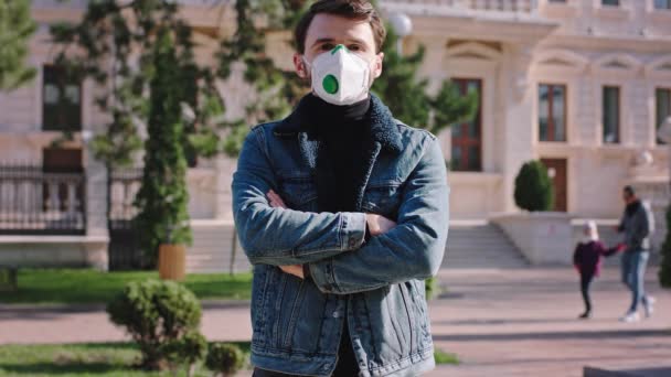 Guy in the jacket outside in the middle of the street standing in front of the camera while wearing a protective mask Coronavirus concept — Stock Video
