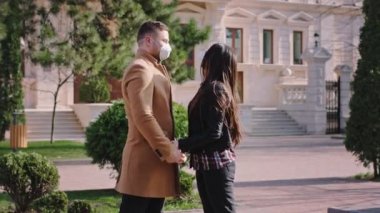 Caddenin ortasında, koruyucu maskeli güzel bir çift yeni Covid-19 'un önünde maskenin üstünde birbirlerini öpüyorlar. ARRI Alexa Mini 'de çekilen