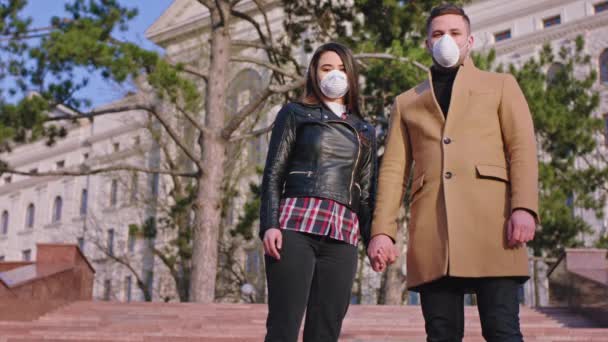 年轻貌美的夫妻站在镜头前，他们戴着防护面具，然后开始走在大街上，Covid-19的概念 — 图库视频影像