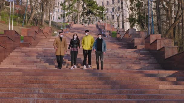 Les jeunes étudiants ont une conversation tout en descendant les escaliers à l'extérieur dans le parc ils portent un masque de protection alors que c'est le Coronavirus 2019. Tourné sur ARRI Alexa Mini — Video