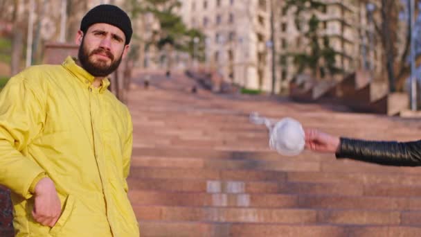 Tos hombre delante de la cámara en el parque sin la máscara una mano de un humano dándole la máscara protectora que llevaba la máscara en su cara tiempo de cuarentena Coronavirus 2019 — Vídeos de Stock