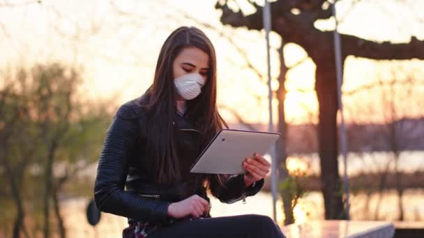 Attraktiv kvinna ensam i parken ta en sitta hon arbetar på sin tablett bär en skyddande mask för att vara säker Covid-19 Pandemic China — Stockvideo