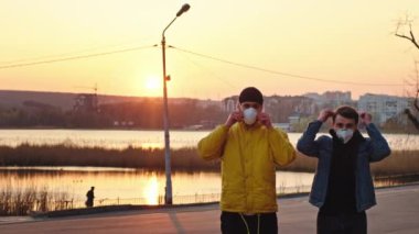 Parkta gün batımında güzel panoramik manzara. Çin 'de N1H1 güvenlik ve sağlıklı konsept kameraların önünde koruyucu maskelerini takan iki adam. 4k
