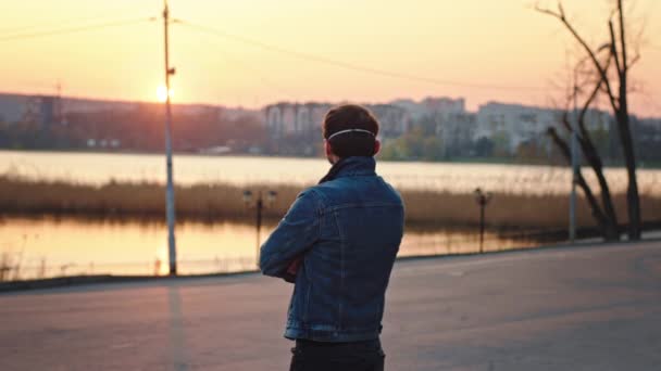 Bell'uomo in piedi davanti alla telecamera guarda il tramonto nel parco vuoto indossa maschera protettiva concetto di vita sana e sicura Covid-19 — Video Stock