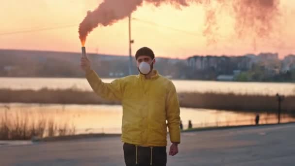 Al tramonto nel mezzo del parco uomo vuoto con una maschera protettiva che tiene una bomba fumogena nel tempo di quarantena nuovo concetto Covid-19 — Video Stock