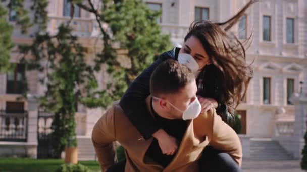 Gelukkig stel in quarantaine in het midden van lege straten hebben een leuke tijd ze dragen beschermende masker dame springen over de mannen terug — Stockvideo