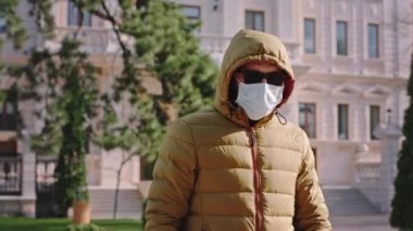 Sokağın ortasında güneş gözlüklü yakışıklı bir adam virüs Covid-19 gittikten sonra koruyucu maskesini çıkardı.