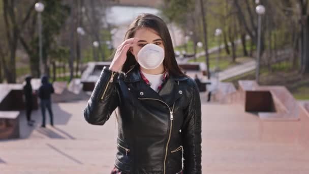 Porträt einer jungen Frau, die inmitten der Parktreppe vor der Kamera steht und die Schutzmaske für diese neue Covid-19 trägt — Stockvideo