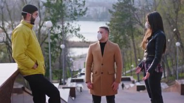 Parkın ortasındaki karantinada bulunan bir grup öğrenci mesafeye saygı göstermeyi ve koruyucu maske takmayı tartışıyorlar, Coronavirus mers kavramı. ARRI Alexa Mini 'de çekilen