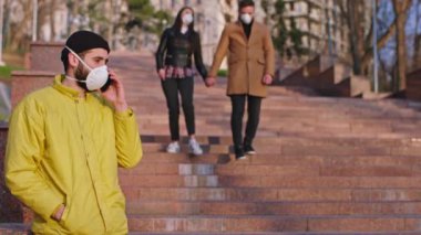 Covid-19 'un karantinaya alındığı sırada yanlarında hapşıran bir çift koruyucu bir maskeyle sokakta yürüyordu.