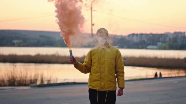 Junger Mann mit Schutzmaske, der im leeren Park vor der Kamera steht, in der Hand eine Rauchbombe Coronavirus 2019 N1H1 — Stockvideo