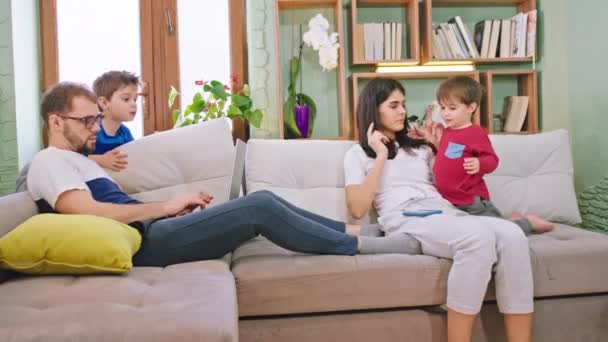 Evde ailesiyle harika vakit geçiriyor. Babaları dizüstü bilgisayarı üzerinde çalışıyor. Anneleri çocuklarla vakit geçiriyor. — Stok video