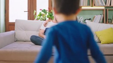 Mutlu ebeveynler çocuklarını kucaklarken kanepede oturup eğleniyorlar. Birlikte eğleniyorlar.