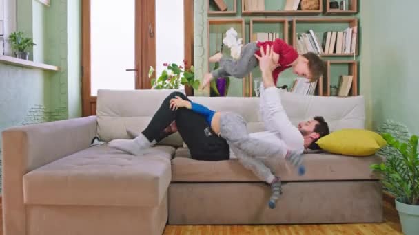 Веселий час для двох дітей і їх батько грає разом, сидячи на дивані перед камерою вони щасливі проводити час — стокове відео