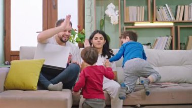 Oturma odasında iki çocuklu, genç ve çekici bir aile kanepede oturmuş birlikte oynayıp gülüyorlar ve harika vakit geçiriyorlar. ARRI Alexa Mini 'de çekilen