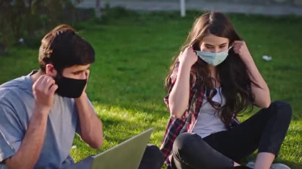 Happy couple stay at home in the garden they take the protective mask off after the pandemic are finished and continue to work on their gadgets — Stock Video