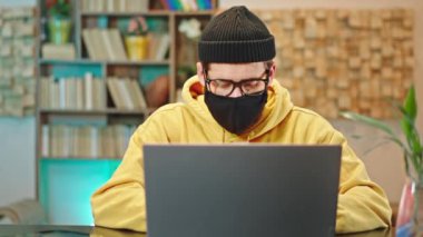 Evinden, koruyucu maskeli bir adamın üniversite kursuna konsantre olduğunu ve konsantre bir yüzün evde kalıp Coronavirus 2019 Çin 'de güvende olmasını sağladığını düşünüyor.