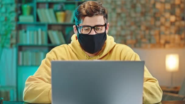 Charismatische Männer mit Schutzmaske im Büro unterhalten sich in der Quarantäne Coronavirus 2019 vor laufender Kamera vom Laptop aus mit anderen Menschen. Schuss auf ARRI Alexa — Stockvideo