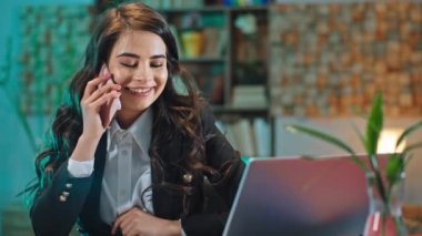 Ofisteki gülümseyen büyük ofis çalışanı iş yerinde otururken telefonda heyecanlı bir konuşma yaptı.