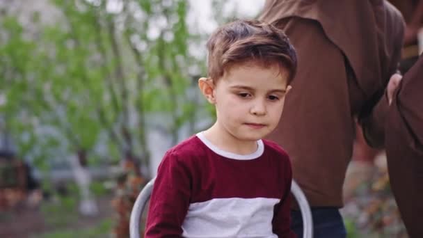 In mezzo al giardino molto divertente piccolo ragazzo si preparano per un barbiere taglio di capelli prendere il grembiule e indossare il bambino — Video Stock