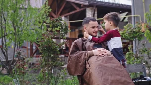 Anak kecil karismatik dan kakaknya bersenang-senang mereka duduk di kebun anak kecil yang lucu mengambil gunting elektronik untuk membuat potong rambut — Stok Video