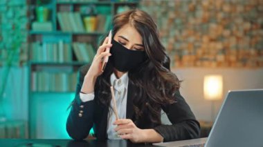 İş yerindeki bayan telefonda konuşuyor. Karantina Coronavirus 2019 'da koruyucu maske takarak önemli bir konuşma yaptı.