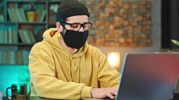 At home in quarantine man with a protective mask working online from home using his laptop new Covid 2019 pandemic China — Stock Video