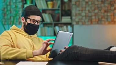 Evde karantinada koruyucu bir maske takarak online Covid 2019 'da öğrenim görüyor.