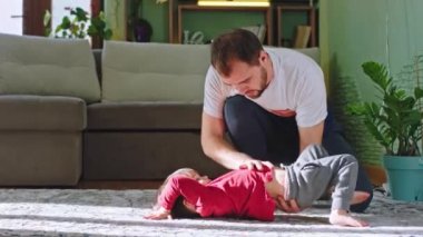 Mutlu baba ve oğlu evlerinde, salonda yerde birlikte egzersiz yapıyorlar. Birlikte vakit geçiriyorlar.