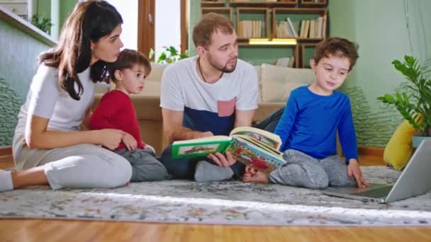 День с семьей внизу на полу в гостиной, читая книгу рассказов, у них дружеская атмосфера — стоковое видео