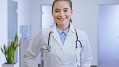Mükemmel bir gülümseme portresi olan genç doktor hanım kameranın önüne bakıyor ve hastane koridorunda kocaman gülümsüyor. ARRI Alexa Mini 'de çekilen