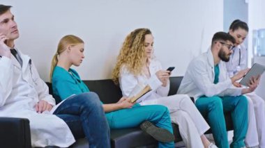 Modern hastane hastahanesinde doktorlar ve hemşirelerin dijital tabletteki bazı hastalıkları analiz etmek için telefonla konuşmaları dinleniyor.