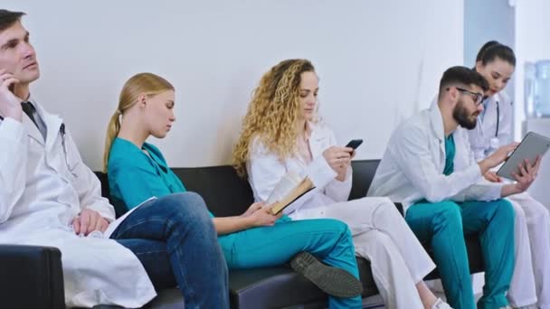 No hospital moderno coisas de médicos e enfermeiros têm uma pausa sentado nos telefones analisando alguma doença do tablet digital — Vídeo de Stock