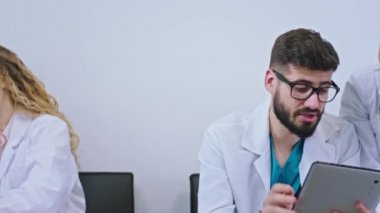 Kameranın önünde, doktorların odasındaki hemşirelerle doktorların arasında ufak bir ara var. Telefonlarıyla sohbet ediyorlar ya da dijital tableti kullanarak bir şeyleri analiz ediyorlar.