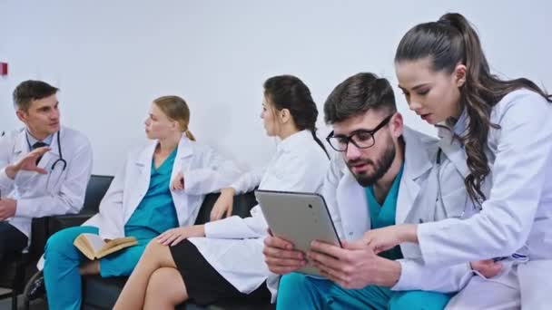 Современная комната больничных вещей во время перерыва группа врачей и медсестер имеют хорошее время социализации они играют некоторые игры на цифровой планшет обсуждения — стоковое видео