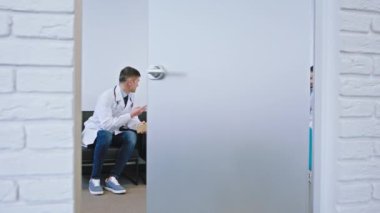 Hastanede, kameranın önünde, dinlenme odasındaki malzeme odasında cam bir kapı açık. Bir grup doktor büyük bir gülümsemeyle harika bir konuşma yapıyor.