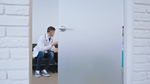 V nemocnici před kamerou jsou otevřeny skleněné dveře v místnosti s věcmi na přestávce skupina doktorů mají skvělý rozhovor s velkým úsměvem
