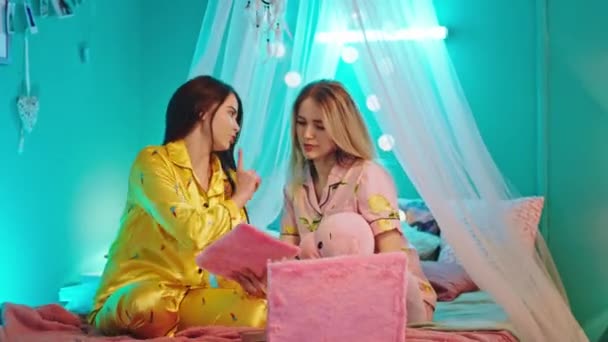 Jovens mulheres bonitas na festa do pijama se divertem conversando juntos melhores amigos gastando tempo juntos usando tablet para ouvir música. 4k — Vídeo de Stock